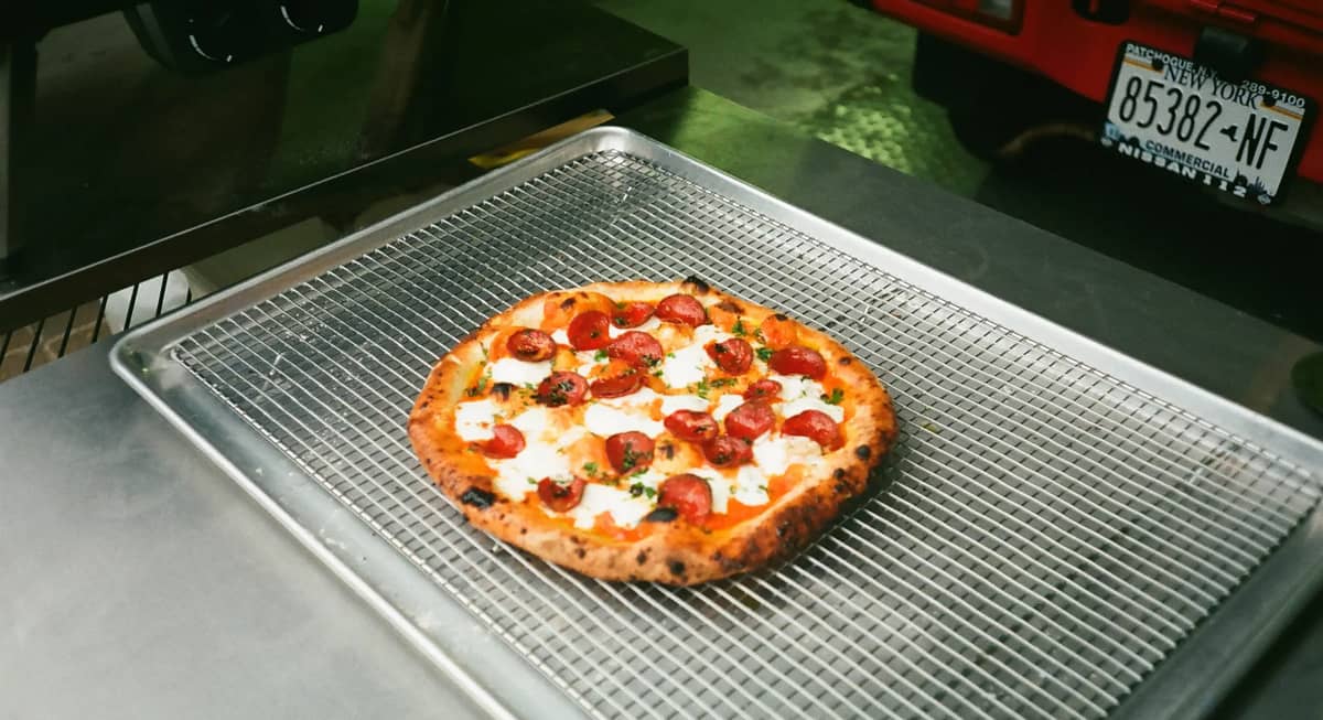 A pepperoni pizza resting on a wire rack beside the truck