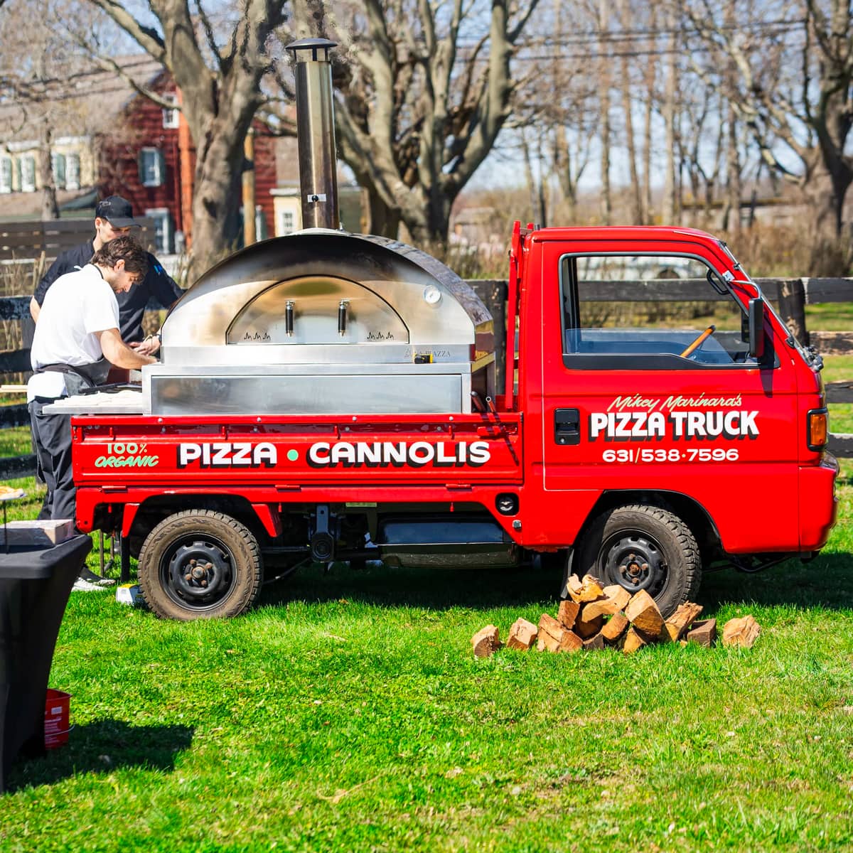 The pizza truck on a back lawn with its wood-fired oven lit