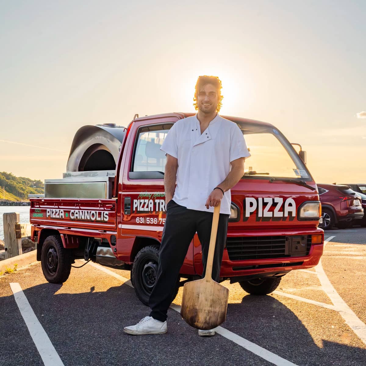 Mikey standing with the pizza truck at sunset