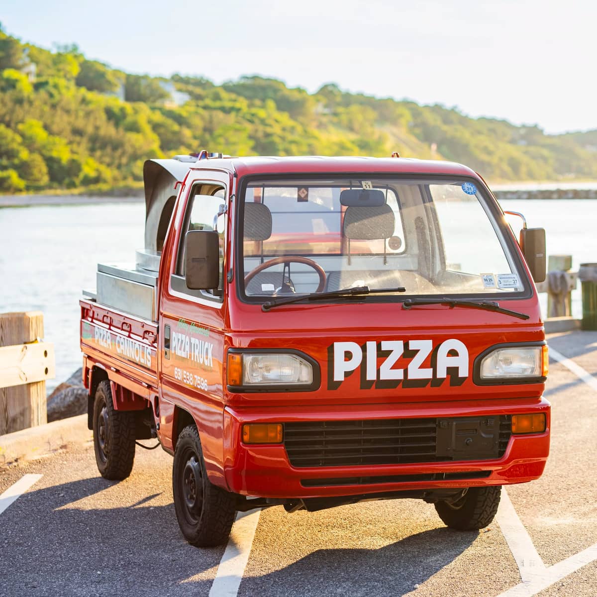 The red pizza truck parked on a waterfront lot