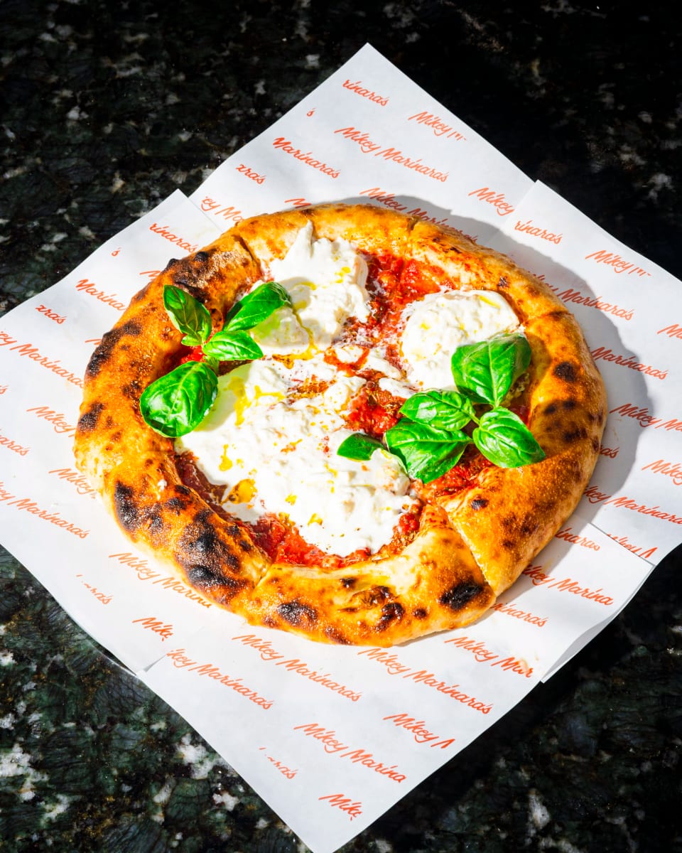 A margherita pizza with fresh mozzarella and basil on branded paper