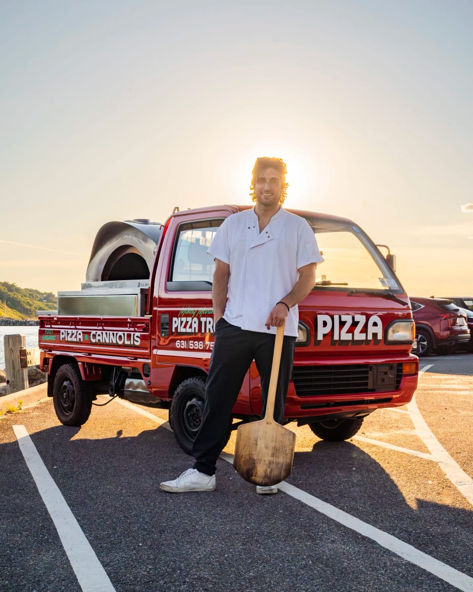 Mikey standing with the pizza truck at sunset